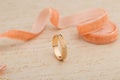 Pink gold wedding ring with diamonds on beige background with ri