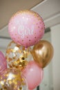 Pink and golden balloons with text `it`s a girl` gender reveal party.