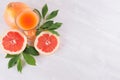 Pink grapefruits juice in elegant glass and grapefruits with green leaf on soft white wood background, top view. Royalty Free Stock Photo