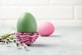 Pink and green Easter eggs in a wicker stand and on a gray table with pussy-willow twigs - Easter composition with copy Royalty Free Stock Photo