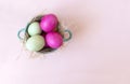 Pink and green eggs in hay vtarelke top view, beige background, Easter