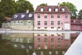 Pink and green old houses reflected in a pond.