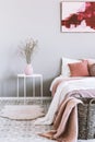 Vertical view of pink and grey bedroom interior with wicker basket and flowers in vase