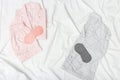Pink and grey pajamas and eye mask on white sheet on bed. Night suit for peaceful sleeping