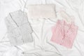 Pink and grey pajamas for men and women, and sleep mask for eye on white cotton bedsheet