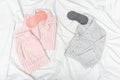 Pink and grey pajamas for two people, and sleep mask for eye on white cotton bedsheet.