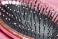 Pink hairbrush close up on a pink wooden background