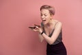 Pink-haired young angry woman shouts on someone on her phone, pink background