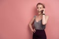 Pink-haired young surprised woman is excited by something she hears on her phone, pink background