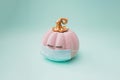 Pink halloween pumpkin with golden petiole and eyelashes and surgical face mask. Green mint background color. Minimal design