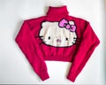 Pink hand-knitted sweater with a drawing of Kitty for a girl on a white background