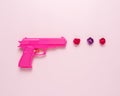 Pink handgun on pink pastel background with flowers. Minimal flat lay concept