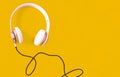 Pink headphone and black cable on pastel color yellow background. Music concept. Royalty Free Stock Photo