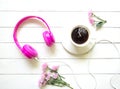 Pink Headphones and coffee cup on wooden desk table with pink flower. Music and lifestyle concept. Top view