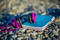 Pink headphones lying at paper notebook on sea beach