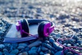 Pink headphones lying at paper notebook on sea beach