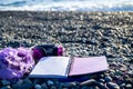 Pink headphones and scarf lying at paper notebook on sea beach