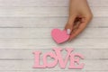 Pink heart in hands closeup on wooden background, near word - love Royalty Free Stock Photo