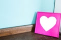 Pink heart picture frame on wood table with blue wall background, space for text