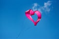 A pink  heart-shaped kite flying in the air against a blue sky background Royalty Free Stock Photo