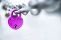 Pink heart shaped lock hangs from bridge chain, symbol of eternal love, copy space