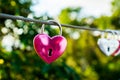 The pink heart shaped love padlock is hanging on wire in blur background Royalty Free Stock Photo