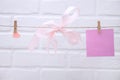 Pink heart with silk bow hanging from a rope with clothespins on a white background.