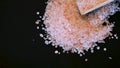 Pink himalayan salt. Himalayan Pink Rock Salt In wooden Spoon on black background. Fine grains of Pink Himalayan salt