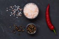 Pink Himalayan salt and mix of peppers in a glasses bowls on the black background. Royalty Free Stock Photo