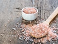 Pink Himalayan salt in spoon on wooden background. Healthy spice closeup