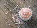 Pink Himalayan salt in white salt shaker on wooden background. Healthy spice closeup