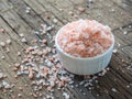 Pink Himalayan salt in white salt shaker on wooden background. Healthy spice closeup