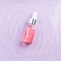 Pink hyaluronic acid serum for face with rose oils in water, top view. Regenerating, hydrating, revitalizing, detoxifying rose oil