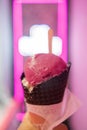 Pink ice cream cone with blurry neon sign on wall as background Royalty Free Stock Photo