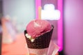 Pink ice cream cone with blurry neon sign on wall as background Royalty Free Stock Photo