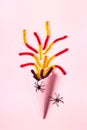 Pink ice cream cone with colorful marmalade worms and spiders. Minimal halloween composition