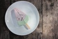 Pink ice cream popsicle in the shape of watermelon on a white plate. Vintage wooden table background with copy space. Summer sweet Royalty Free Stock Photo