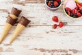 Pink Ice Cream served with berries - strawberries and blueberries in a yellow bowl. Waffle cones with chocolate. Light Rustic Wood Royalty Free Stock Photo