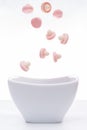 Pink jelly gum drops falling into a white bowl