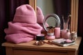 a pink knit beanie on a dressing table with a lamp and a pile of books