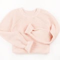 Pink knit sweater flat lay on white background.