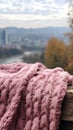 Pink knitted scarf on a wooden table with a view of the city