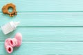 Booties for newborn girl with rattle and bottle on mint green wooden background top view mock up Royalty Free Stock Photo