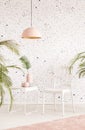 Pink lamp above white chair and table in bright living room interior with plants. Real photo Royalty Free Stock Photo