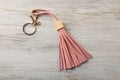 Pink leather keychain on light wooden background, top view