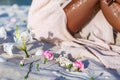 Pink lilies lying on sand foreground and young beatiful woman legs at background on the beach at sunset