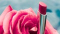 Pink lipstick and rose flower on liquid background, waterproof glamour make-up and lip gloss cosmetics product for luxury beauty