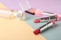 Pink lipsticks with perfume bottle and cosmetics on color background Royalty Free Stock Photo
