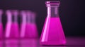A pink liquid is contained in a conical flask, with additional flasks blurred in the background, set against a dark Royalty Free Stock Photo