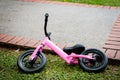 pink little bike for girls parking on the grass and pathway.